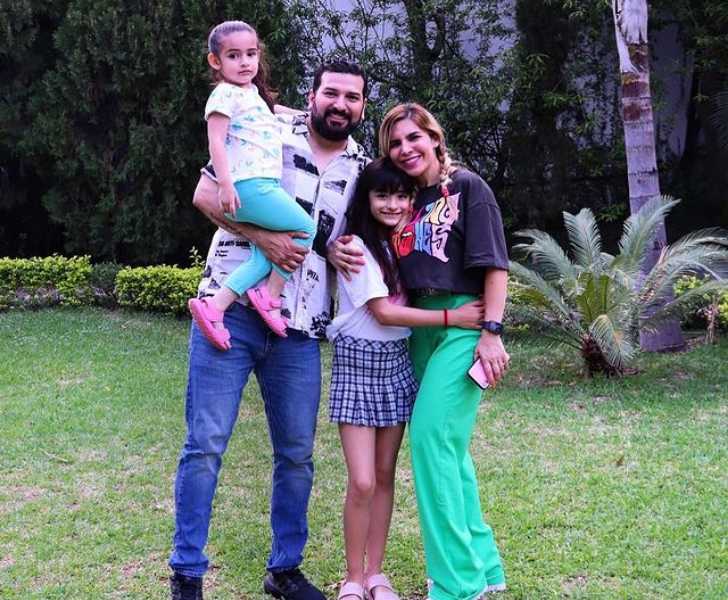 Picture of Karla Panini with her husband Américo Garza and her kids in garden posing for photo.